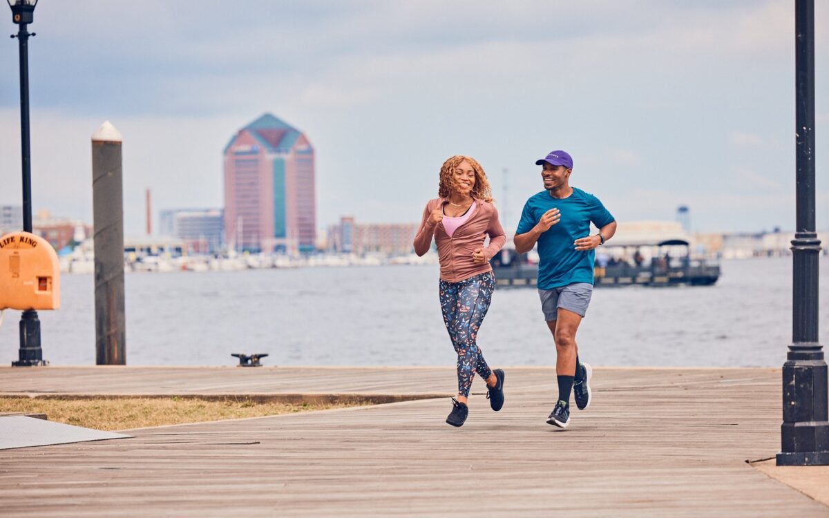 A black man and woman down a pier in front of the water