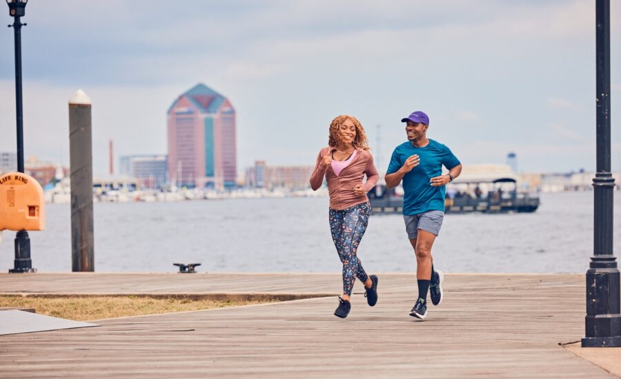 A black man and woman down a pier in front of the water