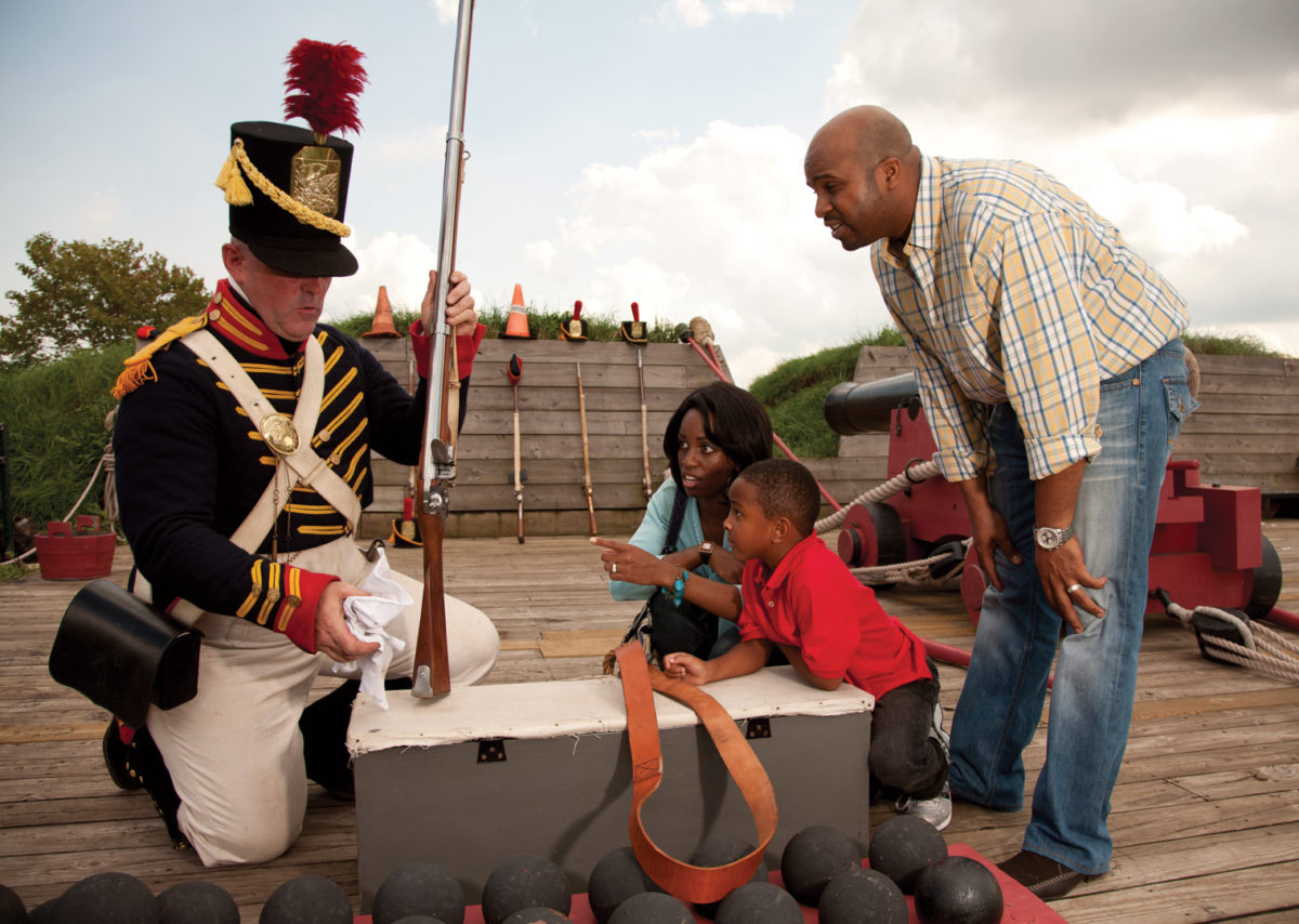 People interact with a marcher behind the ramparts of Fort McHenry.