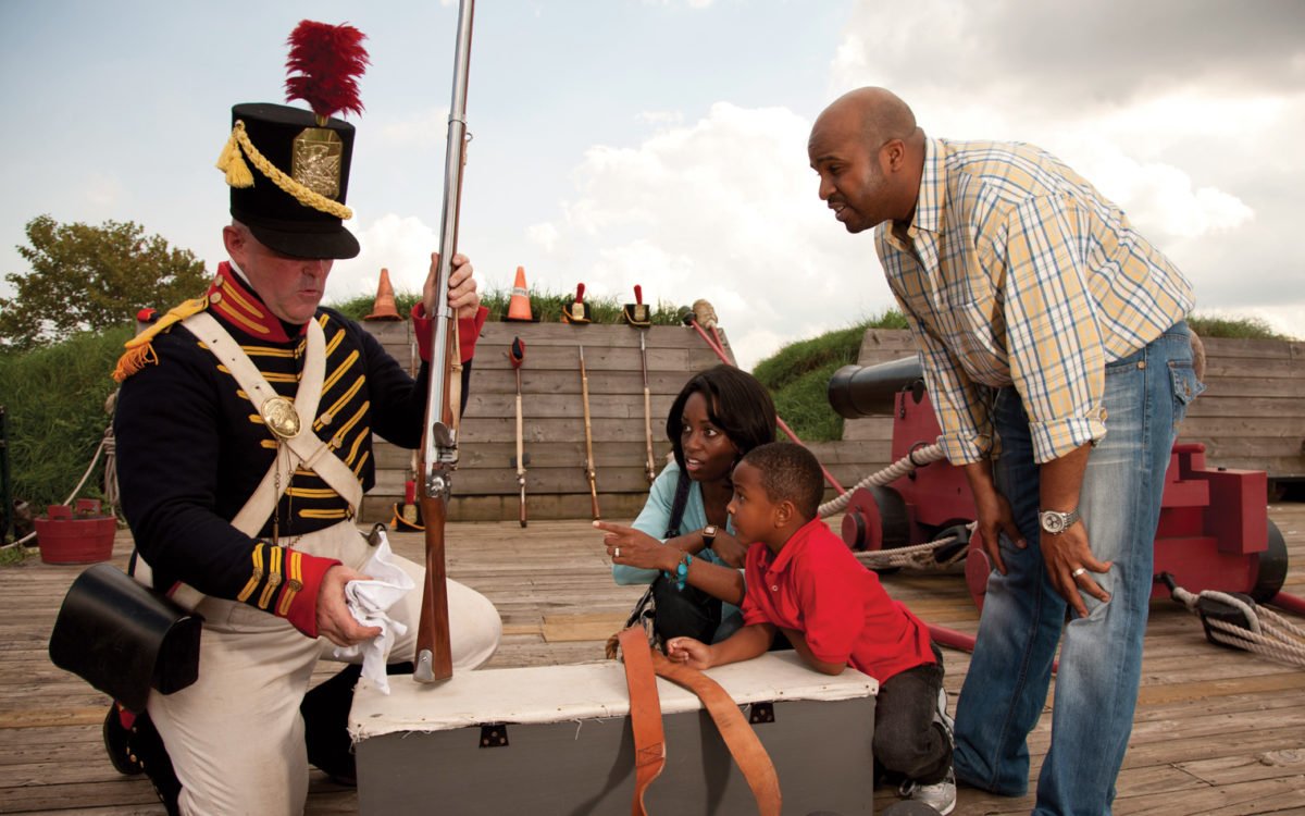 People interact with a marcher behind the ramparts of Fort McHenry.