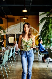 A waitress carries food in a bright restaurant