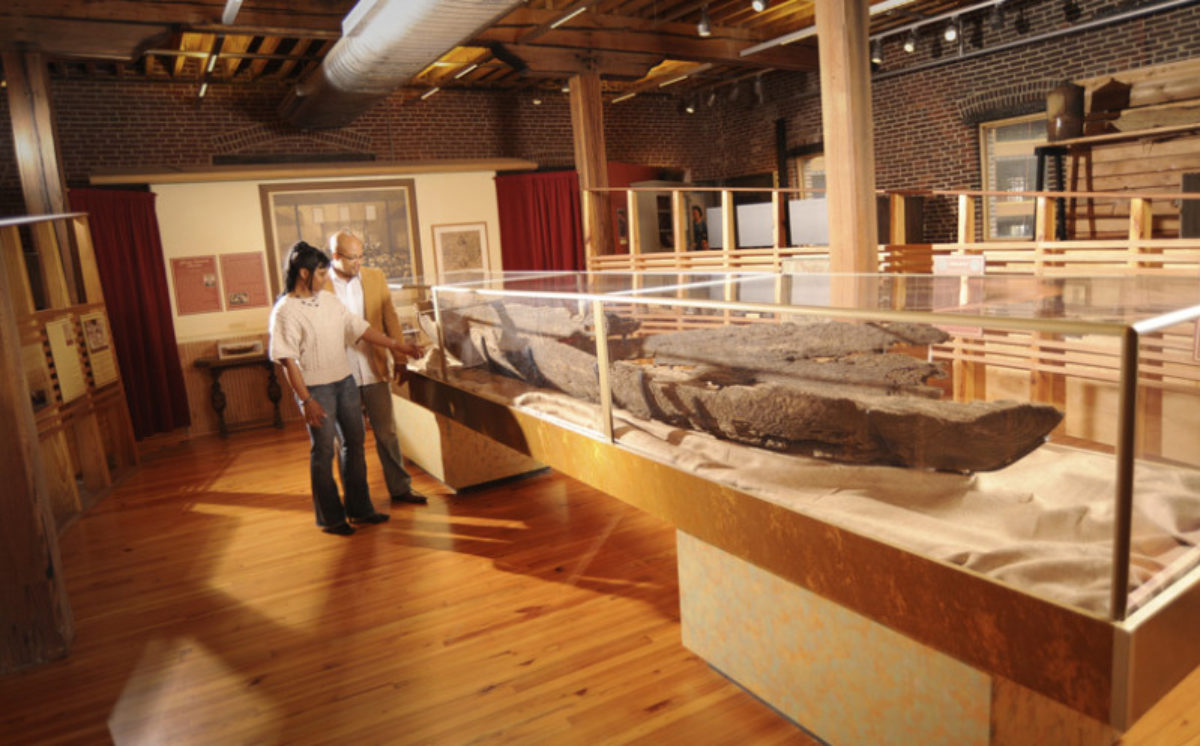 Visitors looking at the remains of a boat in a display case