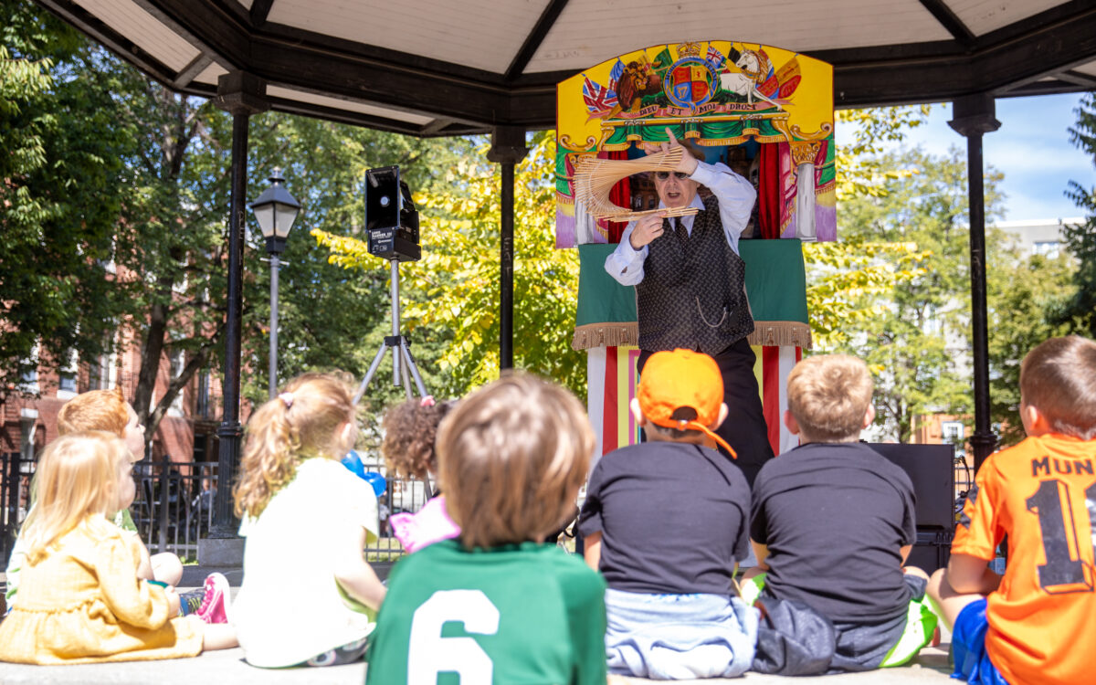 A performer holds up an object to a crowd of children