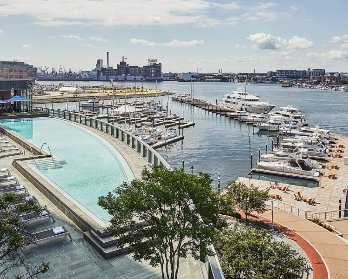Aerial view of the Four Seasons Hotel Baltimore rooftop pool and Baltimore Harbor on a sunny day.