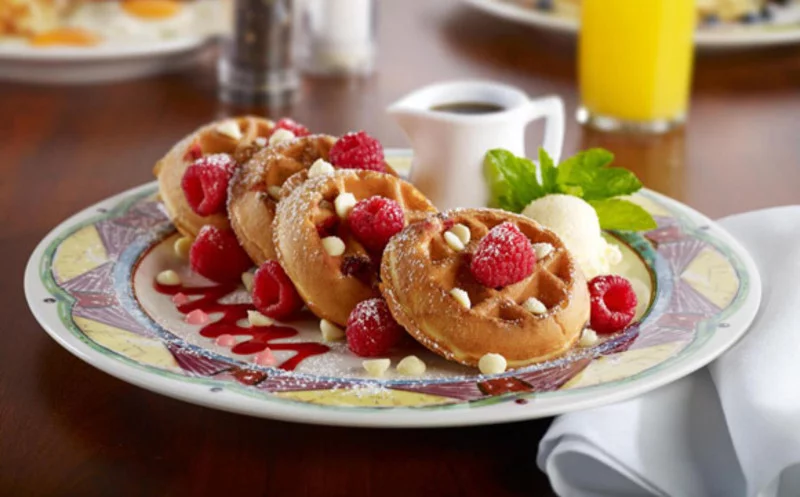 A stack of waffles are topped with fruit and chocolate chips