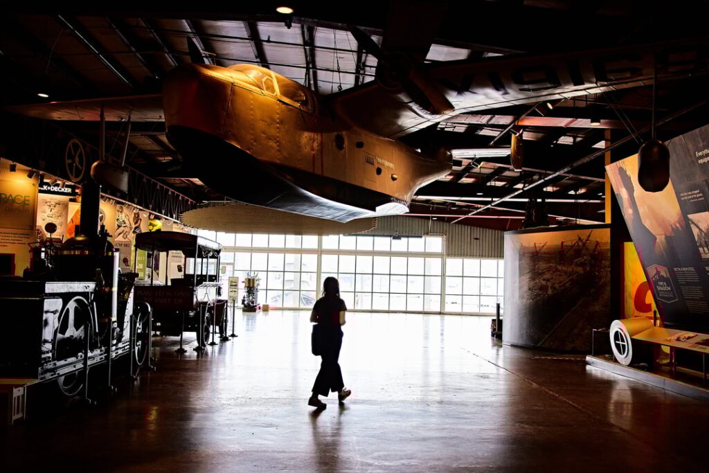 A woman walking through a museum with old objects all around her