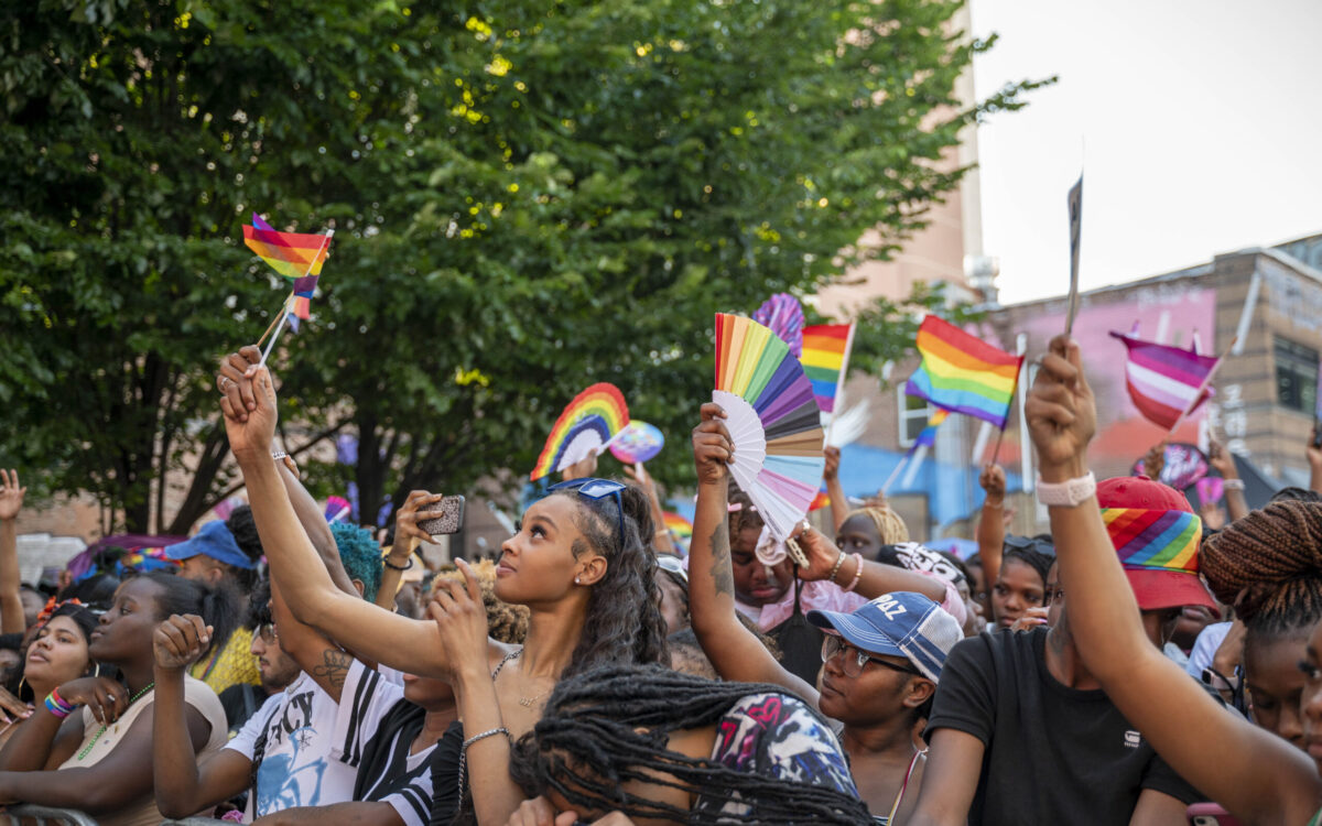 A closer shot of people in a crowd waving rainbow flags
