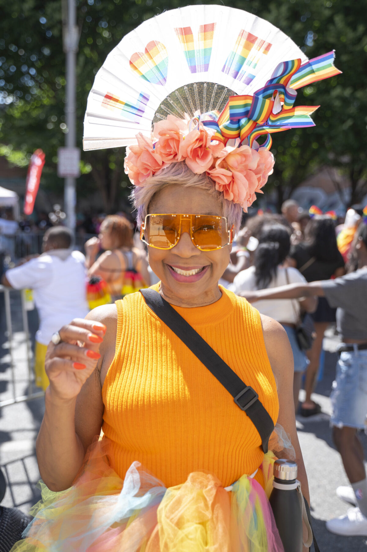 An older woman in a bright orange top wears a head dress that says LOVE