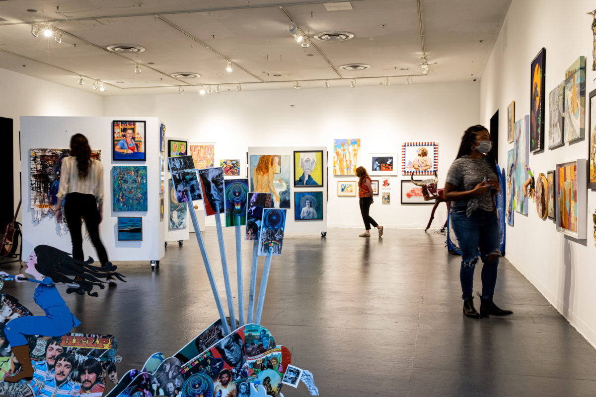 people look at art exhibits inside creative alliance
