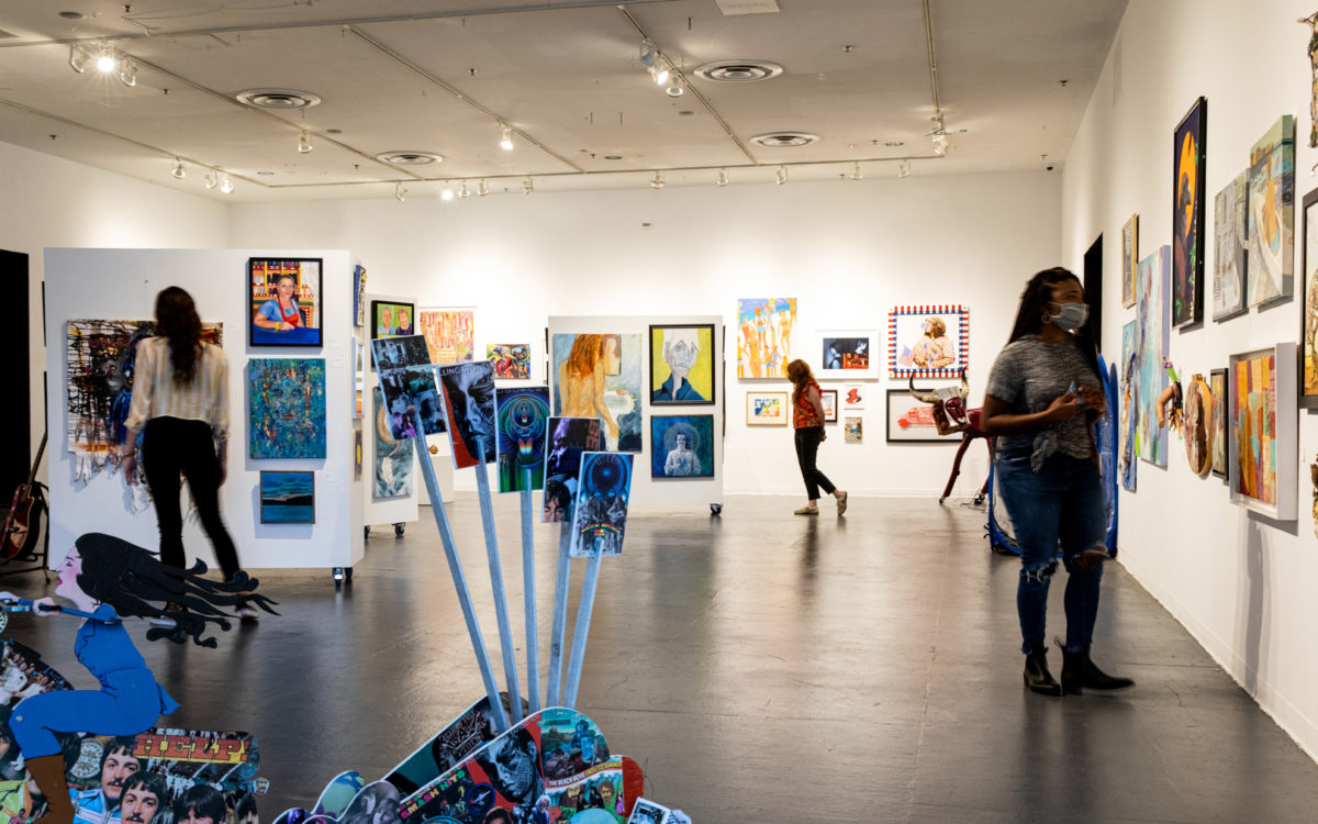 people look at art exhibits inside creative alliance