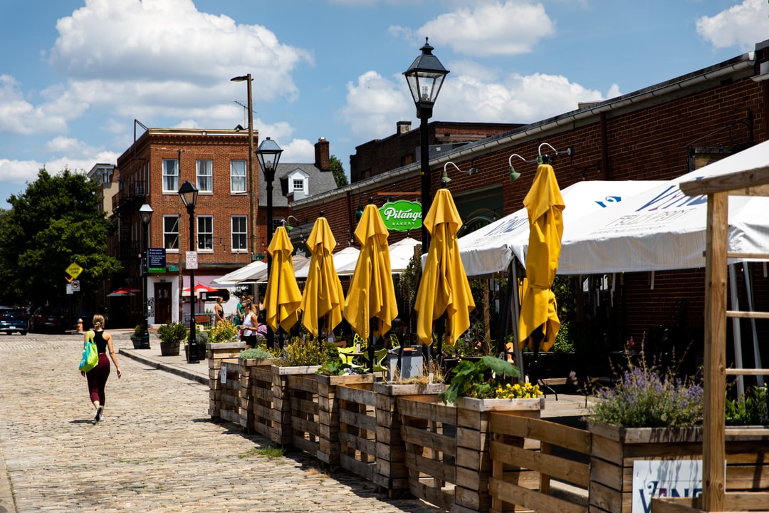 Yellow umbrellas line the cobblestone street outside Pitango Bakery in Fell's Point