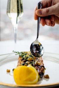 Hand drizzling a topping on an entree