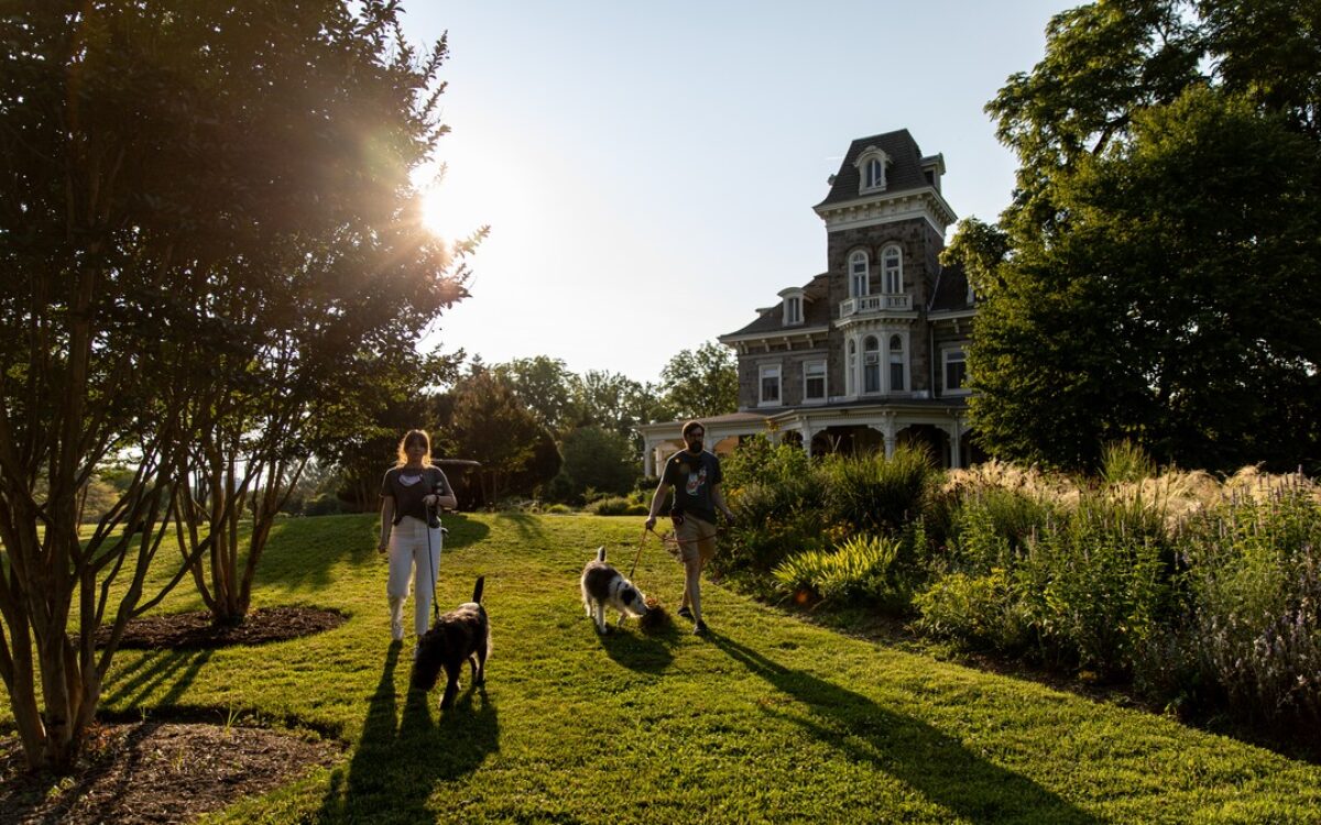 A couple walks a dog outside Cylburn Arboretum