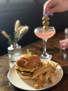 a burger with fries and a pink cocktail